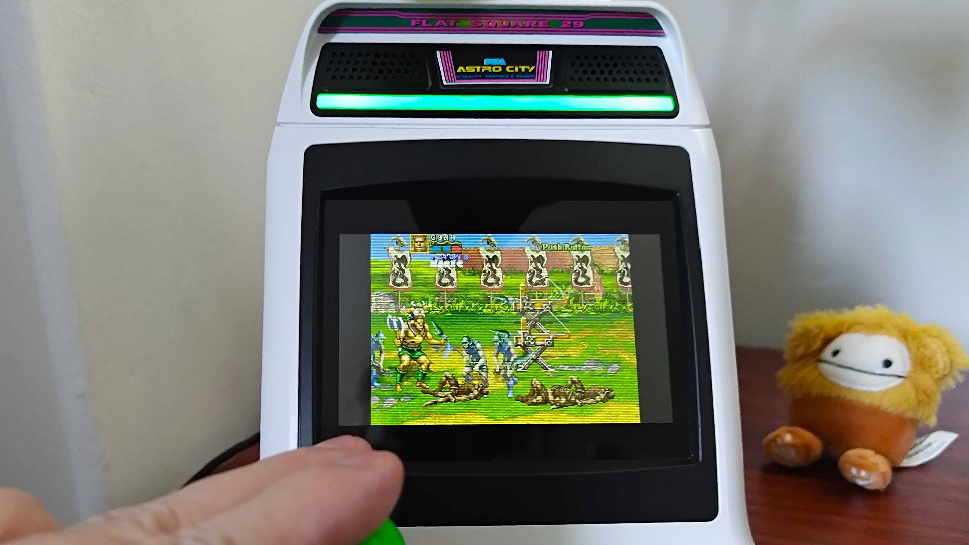 Close up of Sega Astro City Mini with hand using joystick to play Golden Axe: The Revenge of Death Adder.