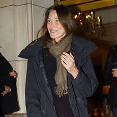 Carla Bruni in Paris wearing a black coat and olive green scarf with a croc-embossed bag