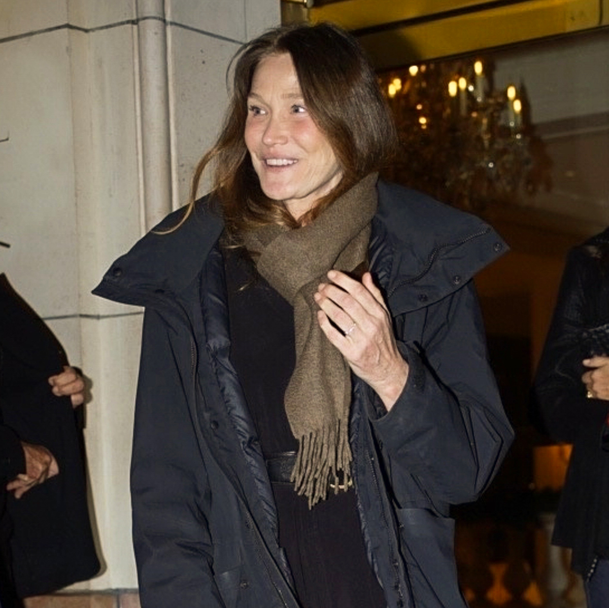 Carla Bruni in Paris wearing a black coat and olive green scarf with a croc-embossed bag