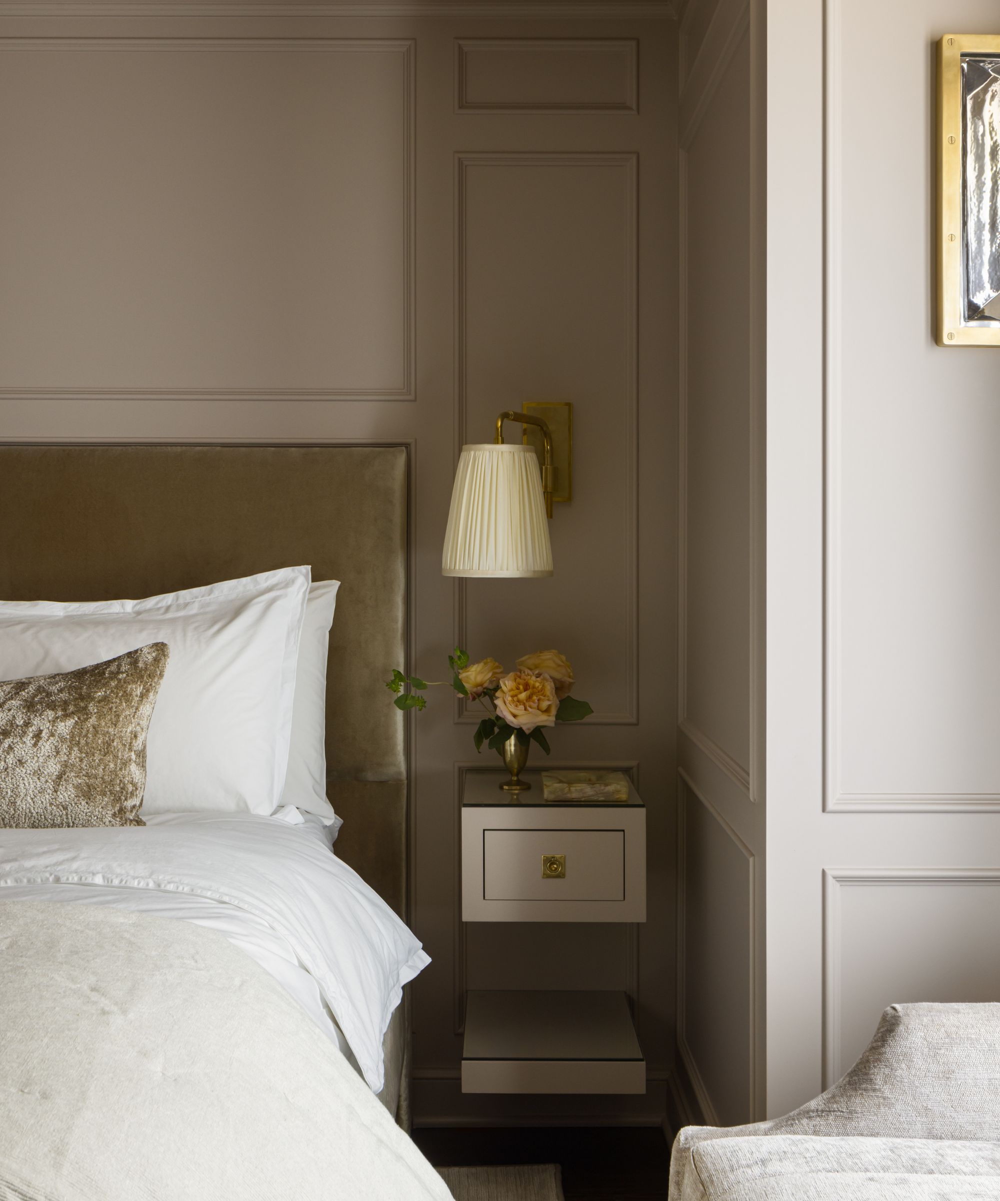 A bedroom with beige wall paneling, an olive headboard with crisp white bedding.