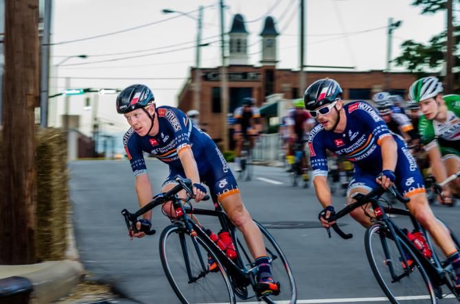 Kevin Mullervy and Isaac Howe of Champion System soft pedal at the front in the pack, while their teammates race up the road in the break.