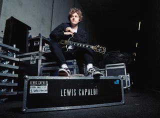 Lewis Capaldi sat with guitar on box