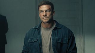 Alan Ritchson as Jack Reacher sitting inside in Season 4 of Reacher. 