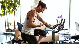 How to get the most out of your exercise bike: image shows woman on exercise bike looking at phone