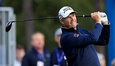 Padraig Harrington watches his tee shot whilst wearing a blue midlayer