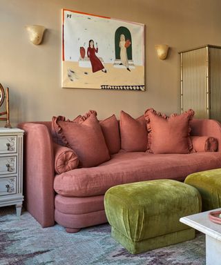 pink couch in a neutral living room with bright green footstools