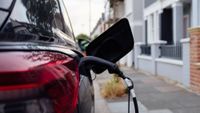 car on residential street with EV charger plugged into it