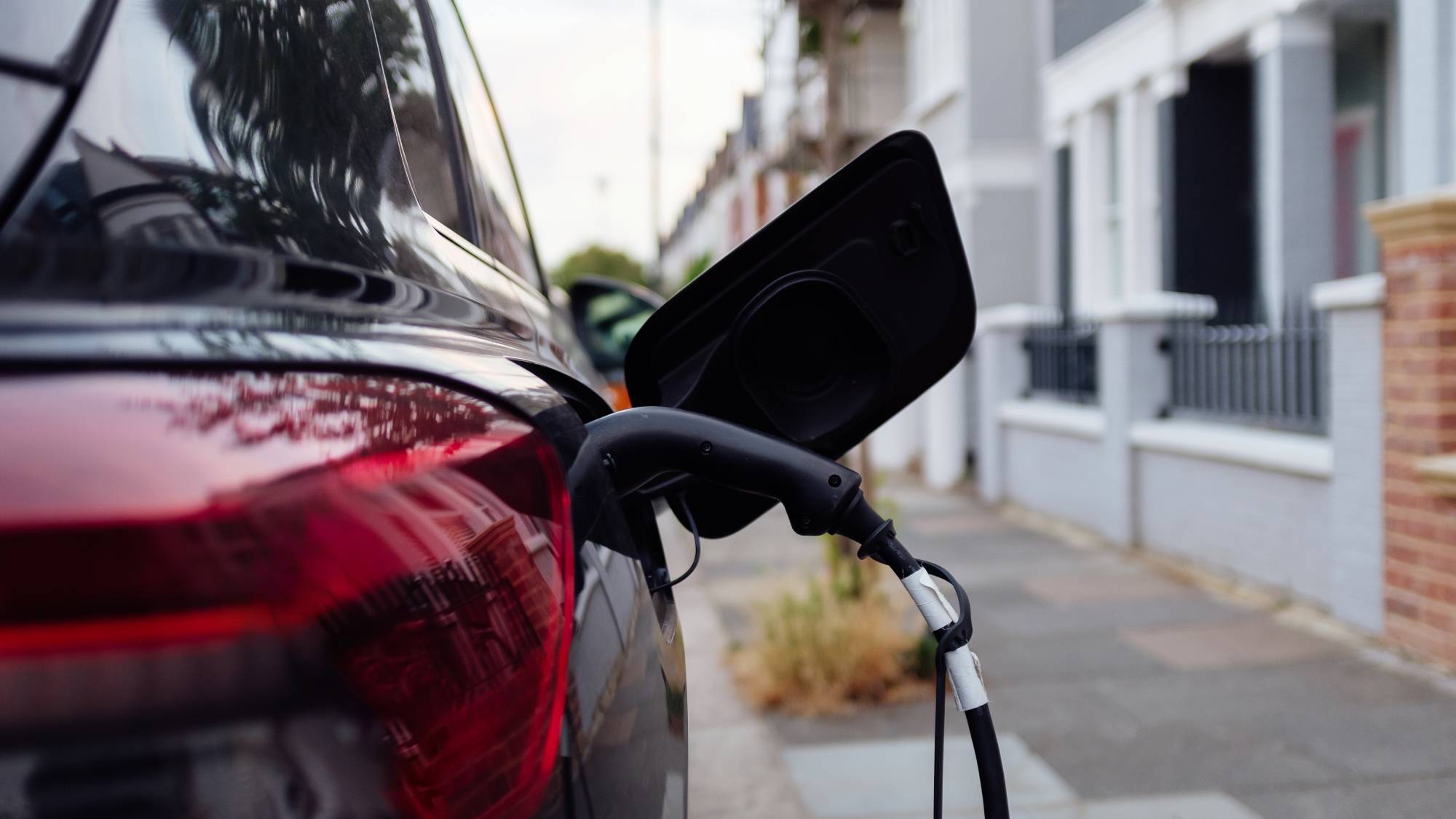 car on residential street with EV charger plugged into it