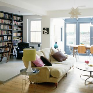 living room with white wall cream colour sofa with cushion book shelves and wooden floor