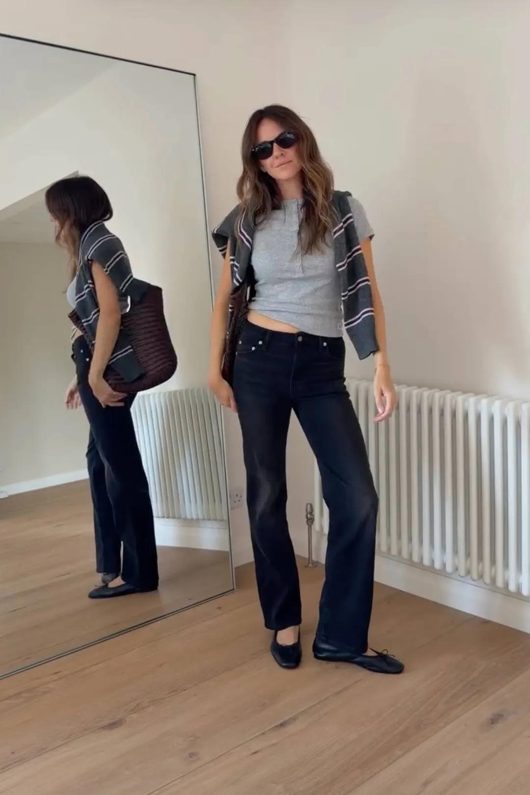 kim wears a gray henley with black jeans and a stripe sweater.