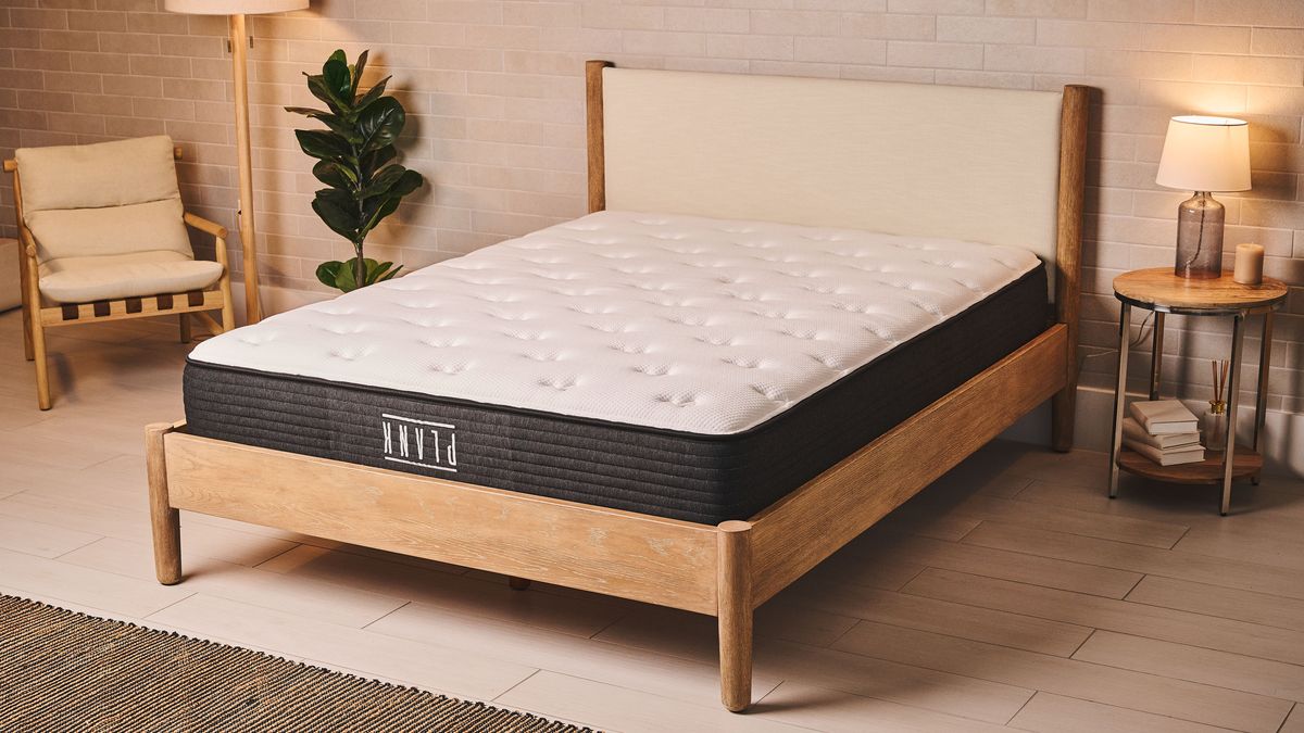 Our best firm mattress of 2025, the Plank Firm mattress with the Firm side facing upwards, on a wooden bed frame in a bedroom