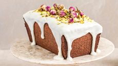 rosewater cake topped with icing and pistachios and dried roses