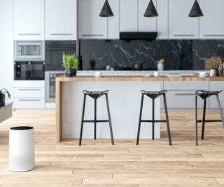 An air purifier in the corner of an open-plan kitchen with an island in the middle