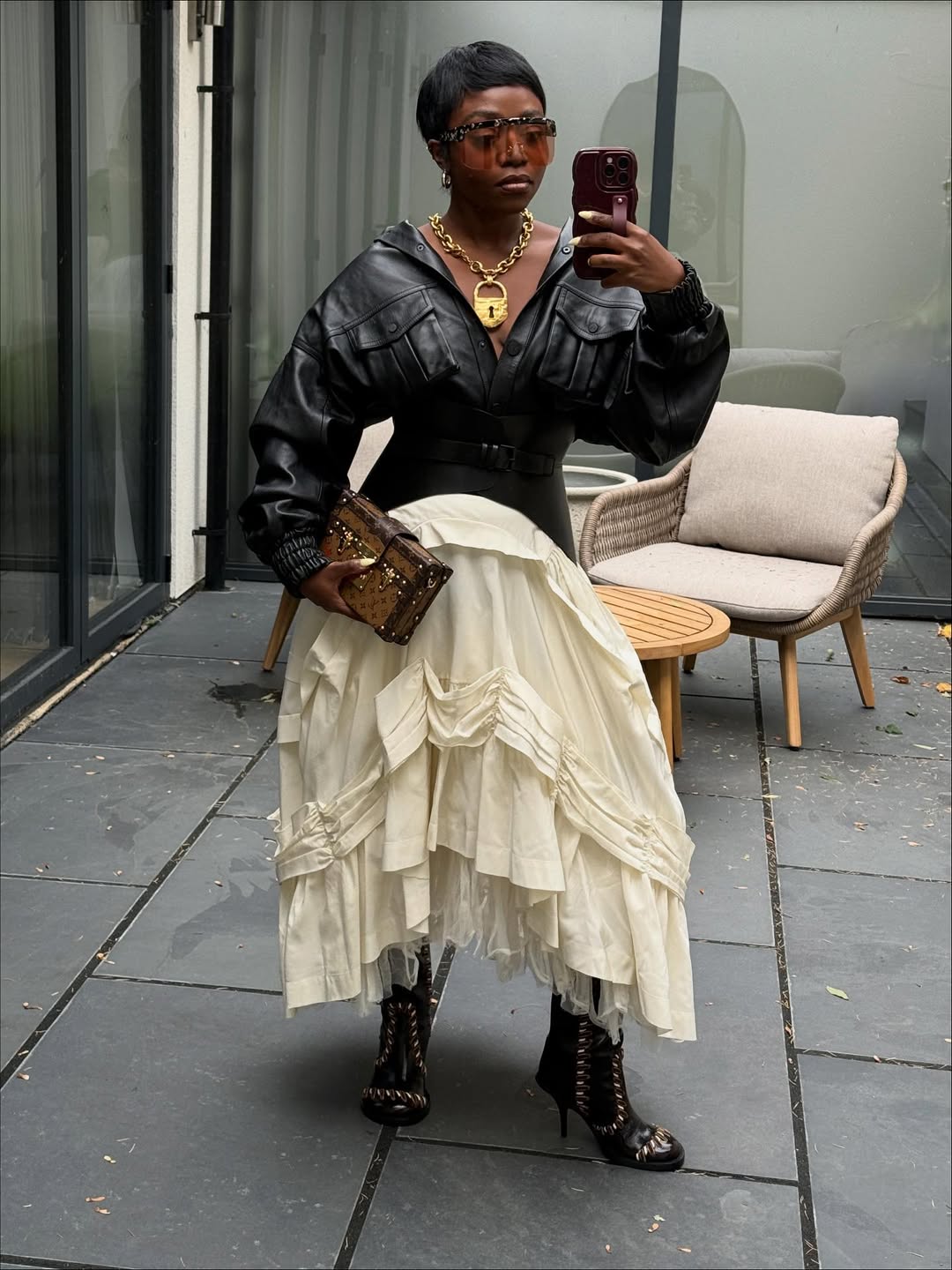 fisayo longe posing in a white skirt, black leather jacket and heeled boots