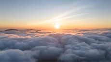 The sun rises above the clouds.