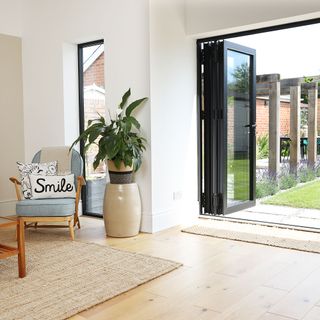 Corner of a living room with bi-fold doors and a chair with smile cushion