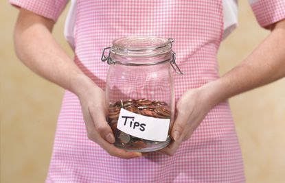 Image of a woman holding a tip jar. 