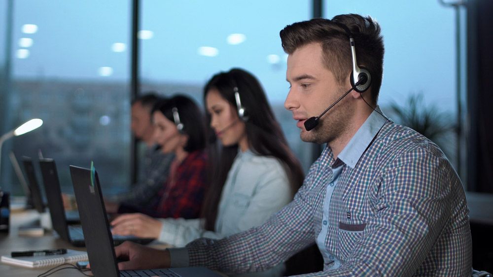 Four call-center workers using laptops.