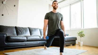 A man performing a lunge with dumbbells as part of a home leg workout