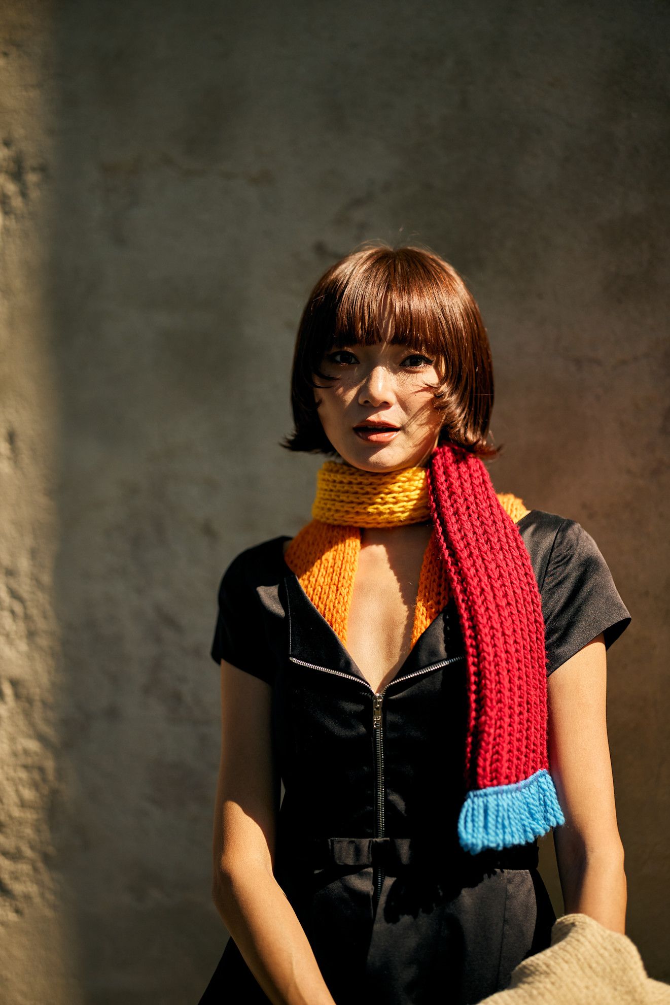 an asian woman with a red bob wearing a knit red scarf