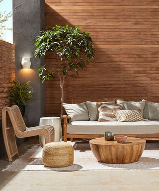 An outdoor furniture setup in front of a paneled wooden wall