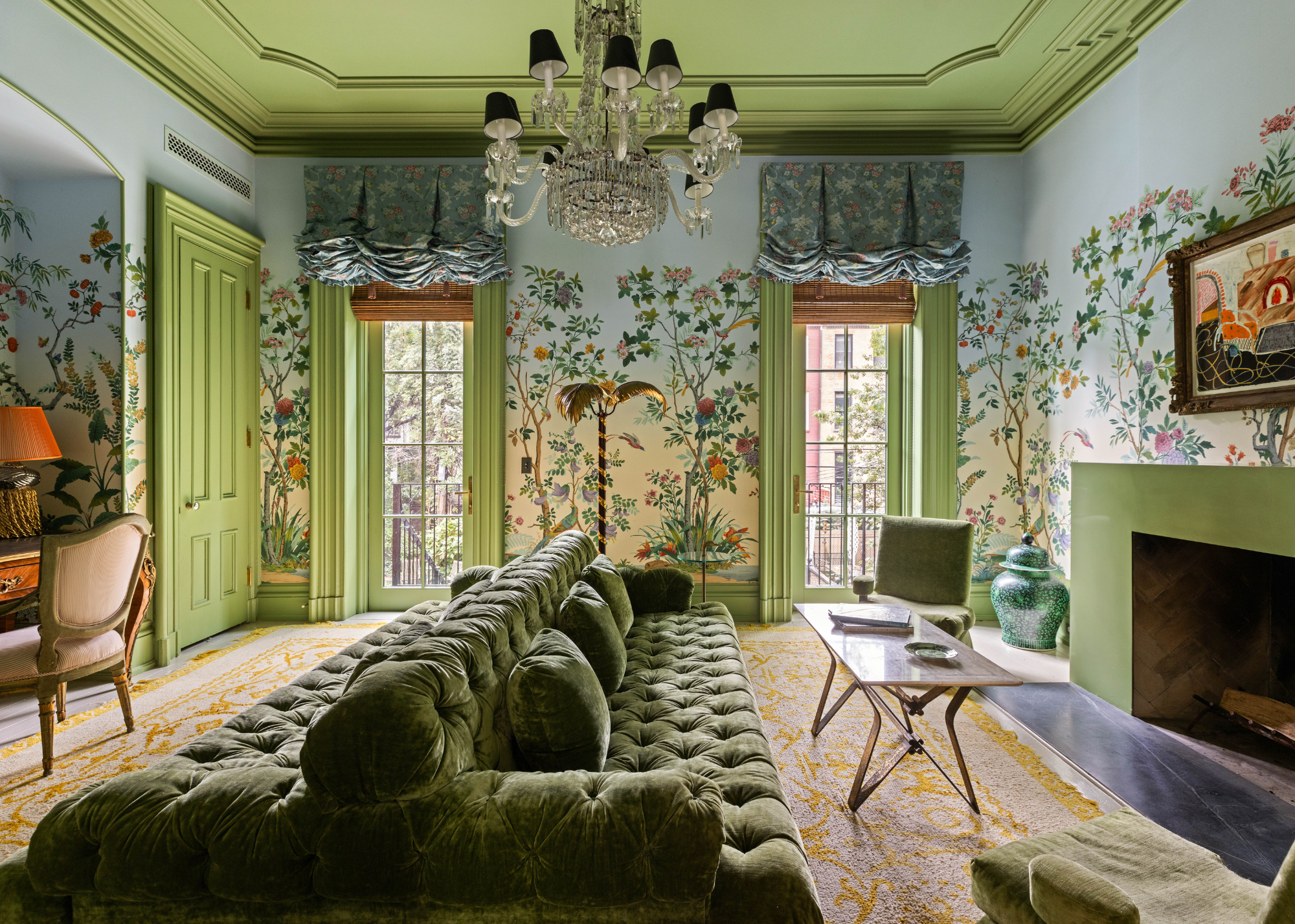 extravagant living room with mural wallpaper and green details as well as a large green sofa in the middle of the room