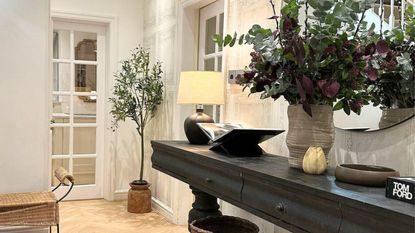 Small entryway lighting mistakes are avoidable, Here is a well-placed lamp on a black console table, in a white entryway