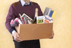 A senior man carrying a box of possessions after retiring