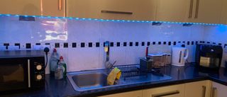 WiZ LED Strip smart lights stuck to the underside of kitchen cabinets, lighting the room blue