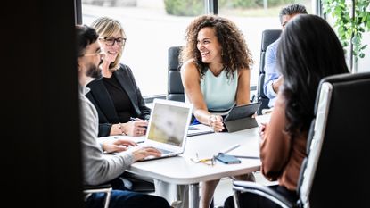 Soft skills concept image showing diverse team having a meeting in an open plan office space to discuss AI strategy and digital transformation plans.