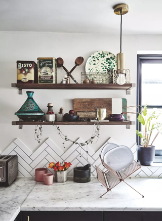 A white kitchen with marble worktops and wooden shelving