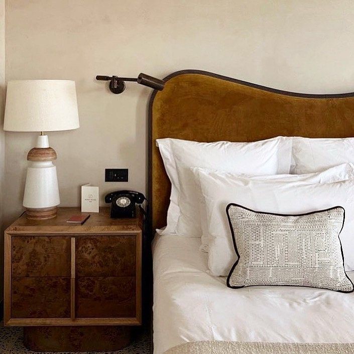 Tempat tidur dengan bantal dekoratif dan meja samping tempat tidur