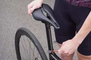 Image shows a rider adjusting their bike saddle height.