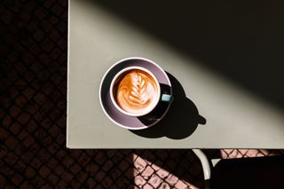 A bird's eye view of a cup of cappuccino with latte art on the table.