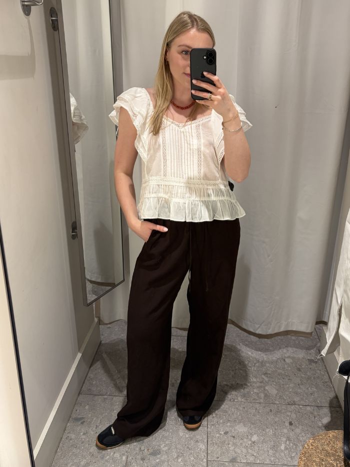 Woman wears white blouse, brown linen trousers