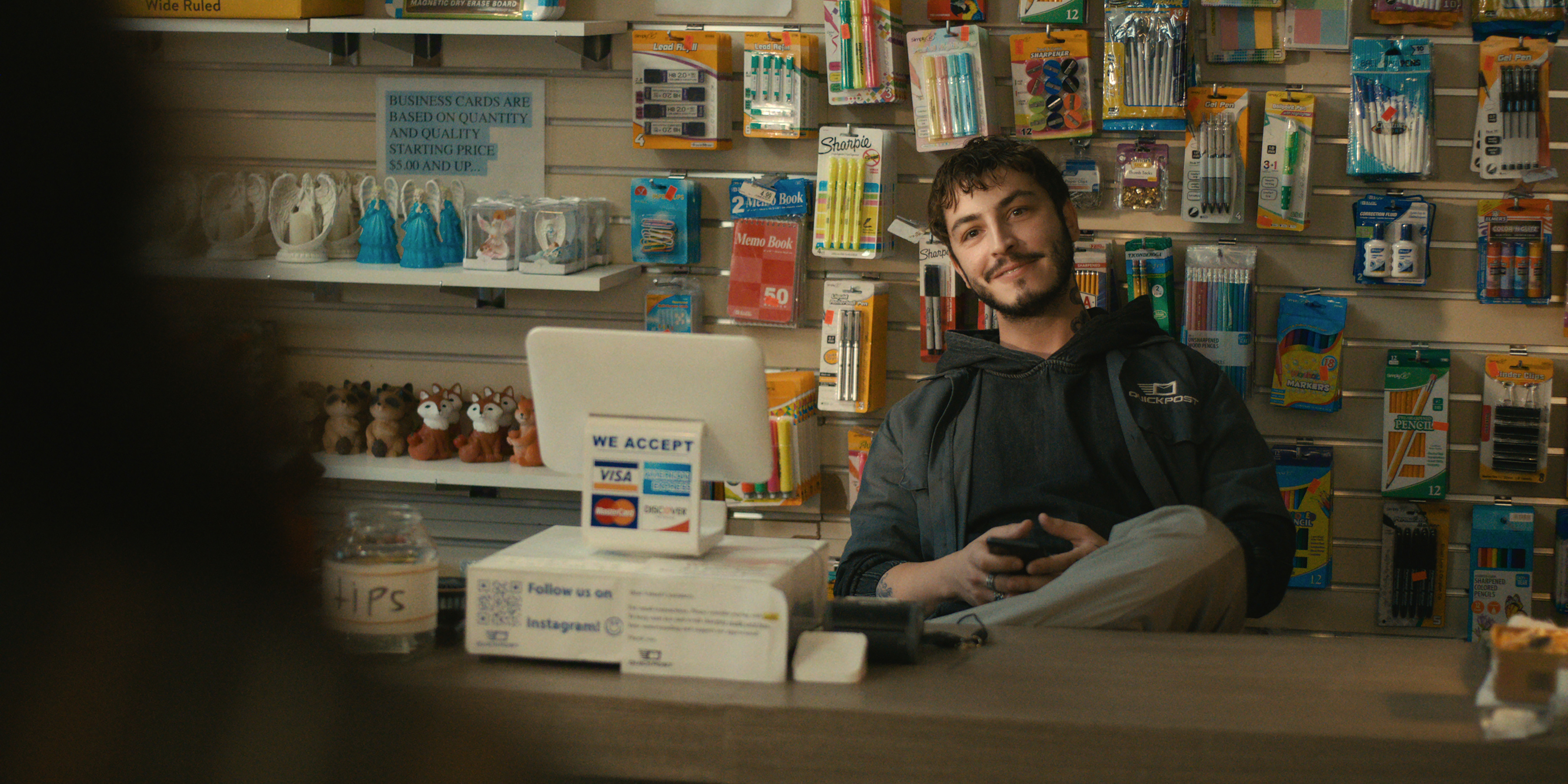 Boran Kuzum as Yusuf sits behind a store counter in Episode 101 of Big Mistakes.