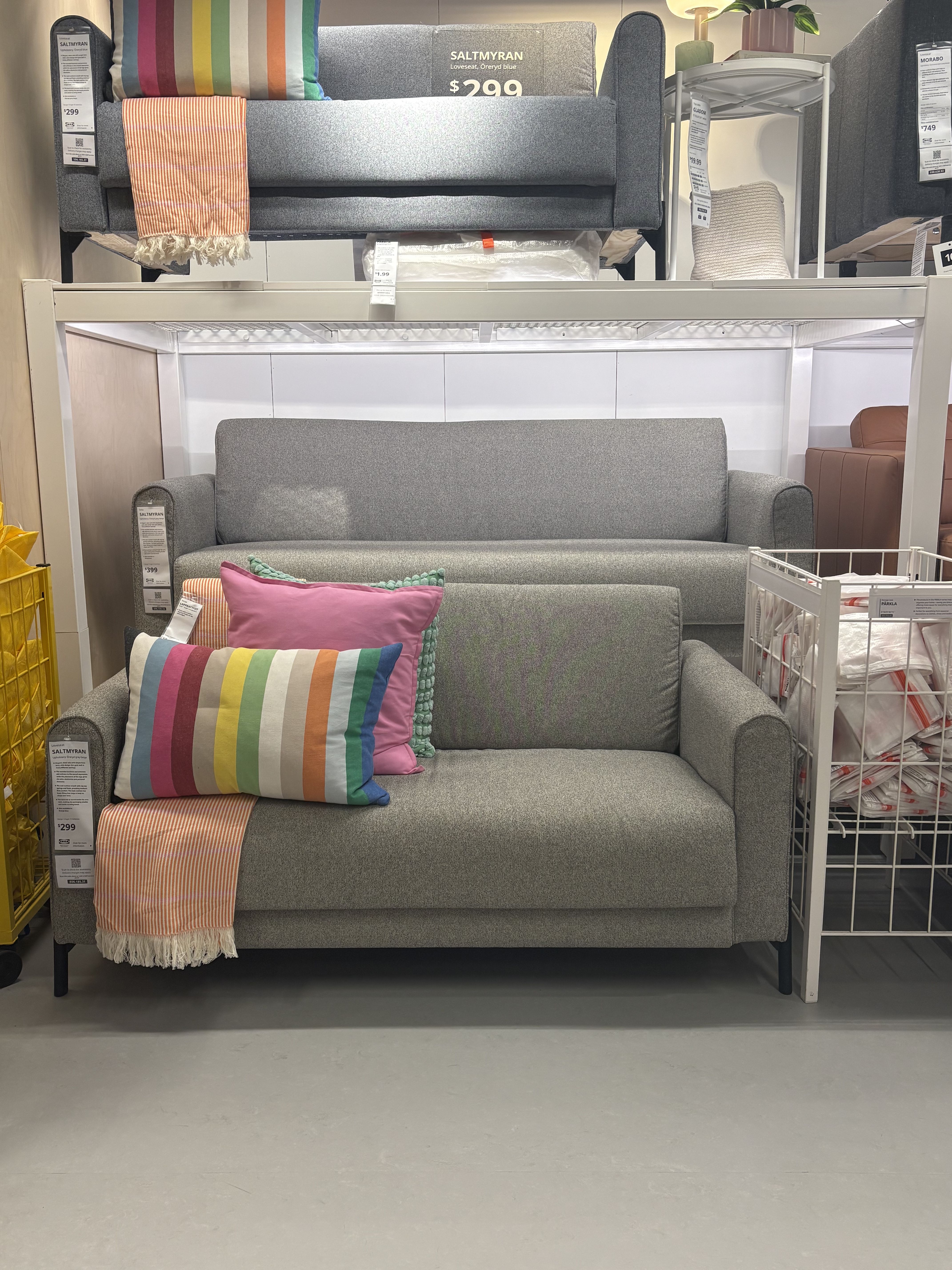 A gray sofa with multicolored pillows sitting in a showroom.