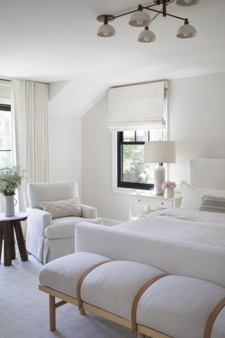 A bedroom in cream and white with a white armchair