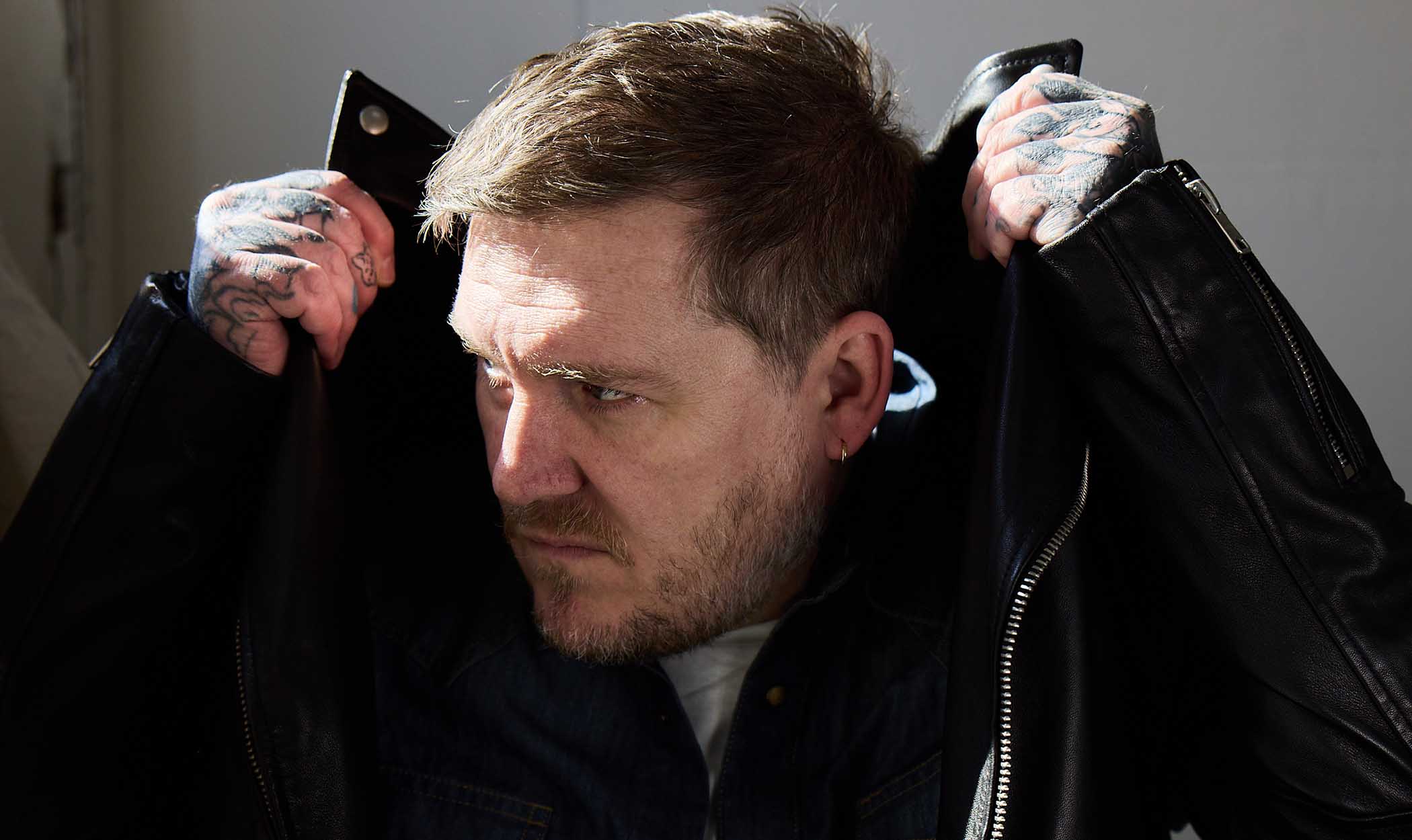 Brian Fallon pulls a leather jacket over his head