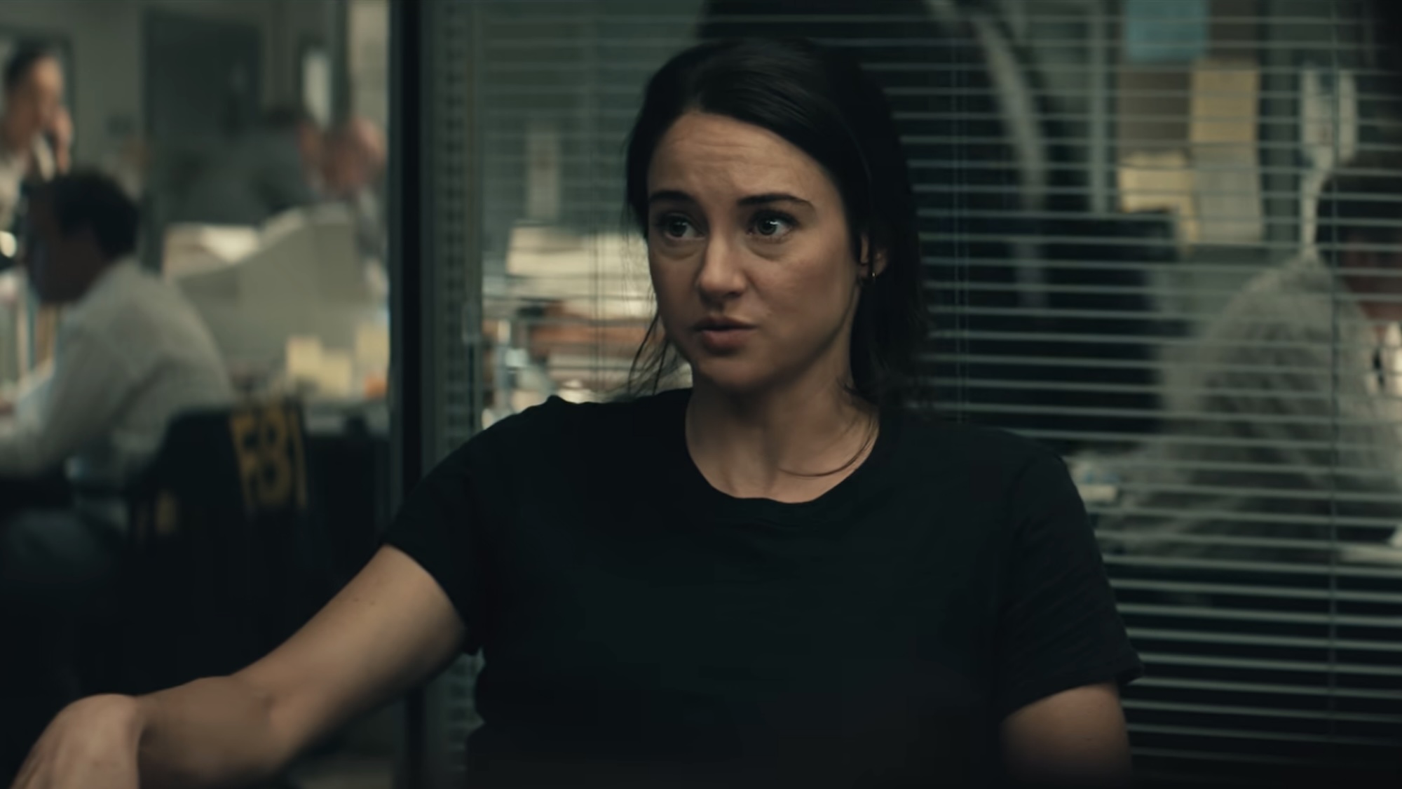 Shailene Woodley wearing a t-shirt and talking about the manhunt in an office during Unabomber.