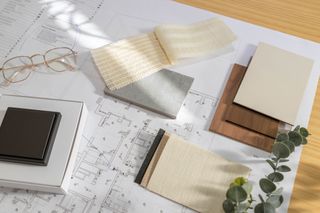 a physical mood board with cream fabric samples and wood samples.