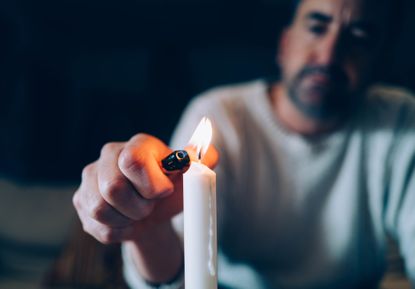 Man lighting a candle on black background