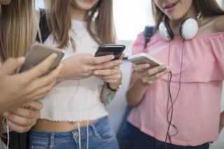 A close up of three girls on their phones