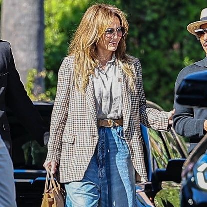 Jennifer Lopez walks in Los Angeles carrying a tan birkin bag with a plaid blazer and high-rise baggy jeans