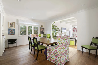 A dining room with green chairs, and a pink and green patterned accent chair