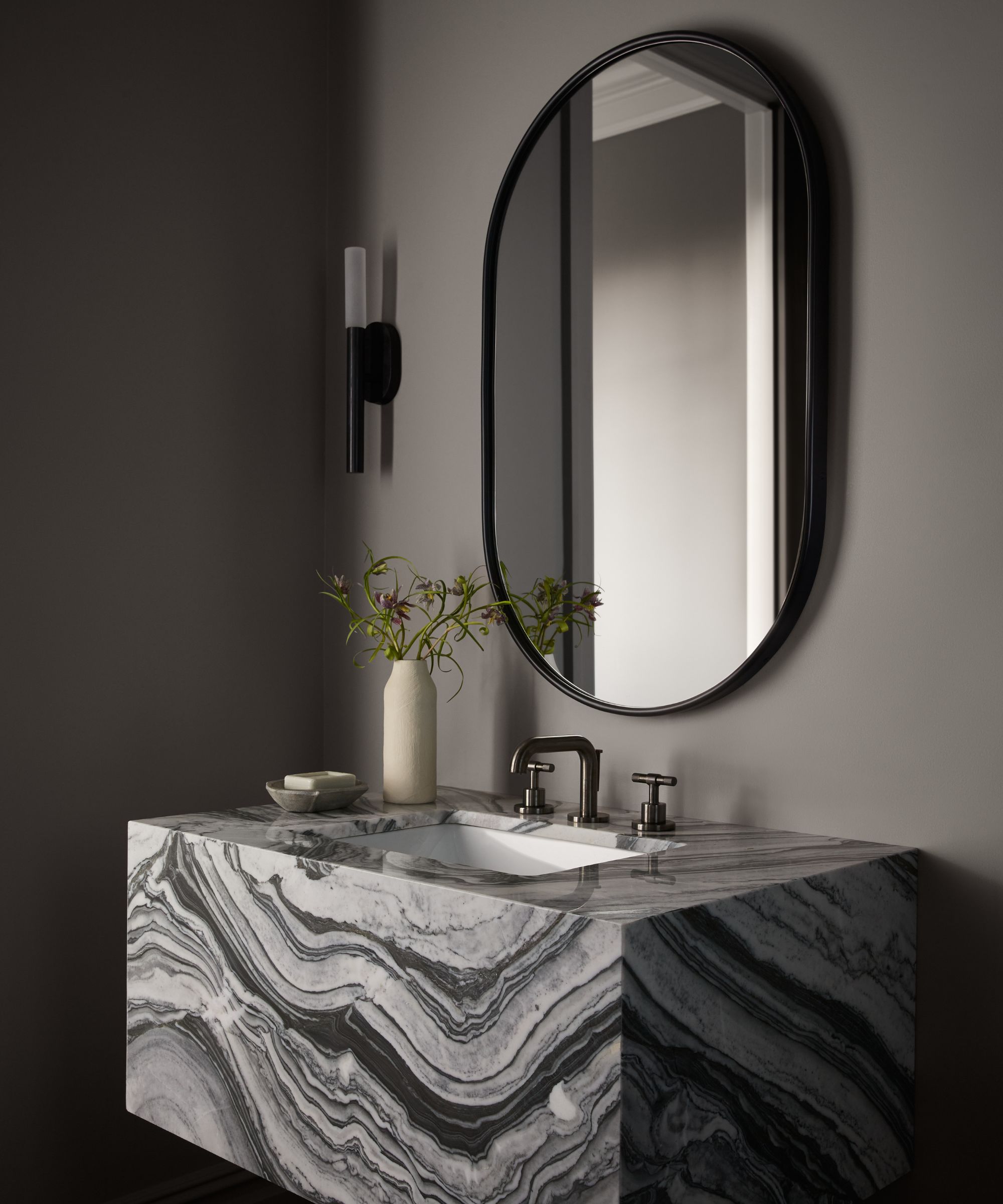 marble vanity unit with mirror and dark walls