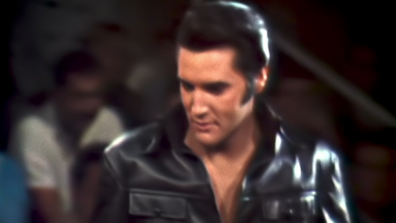 Elviss Preslijs valkā melnu ādu un skatās uz leju
