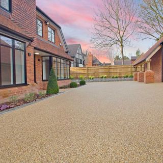 Resin driveway outside a brown double story house