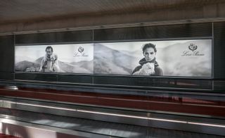 Two side-by side advertising boards for Loro Piano. The left image shows a white male holding a lam around the male's neck. The right image shows a white female holding a lamb in her arms. The backdrop in both photos are of hill landscapes.