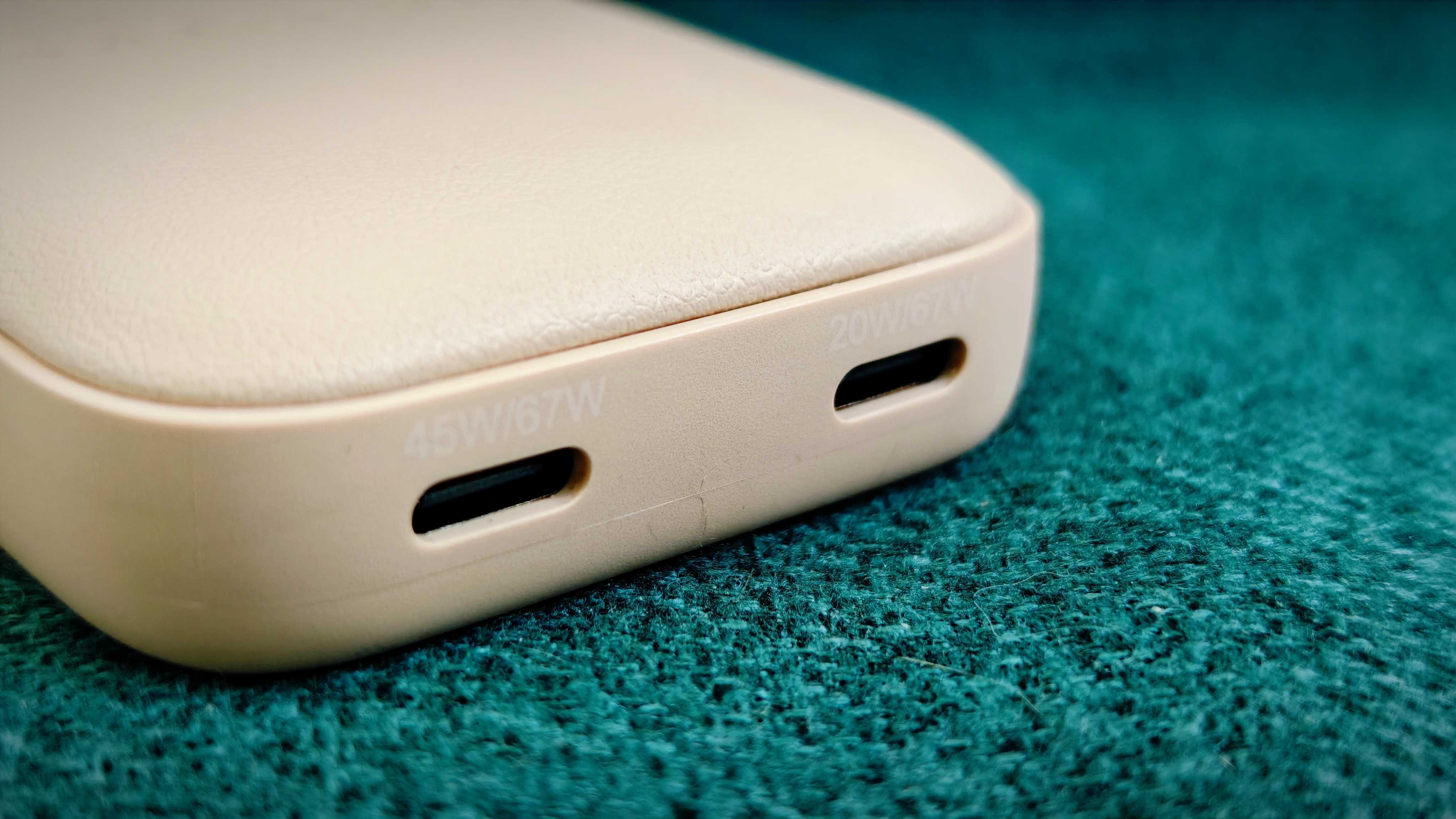 A Desert Rose coloured Satechi OntheGo 67W Slim Wall Charger on a green fabric sofa